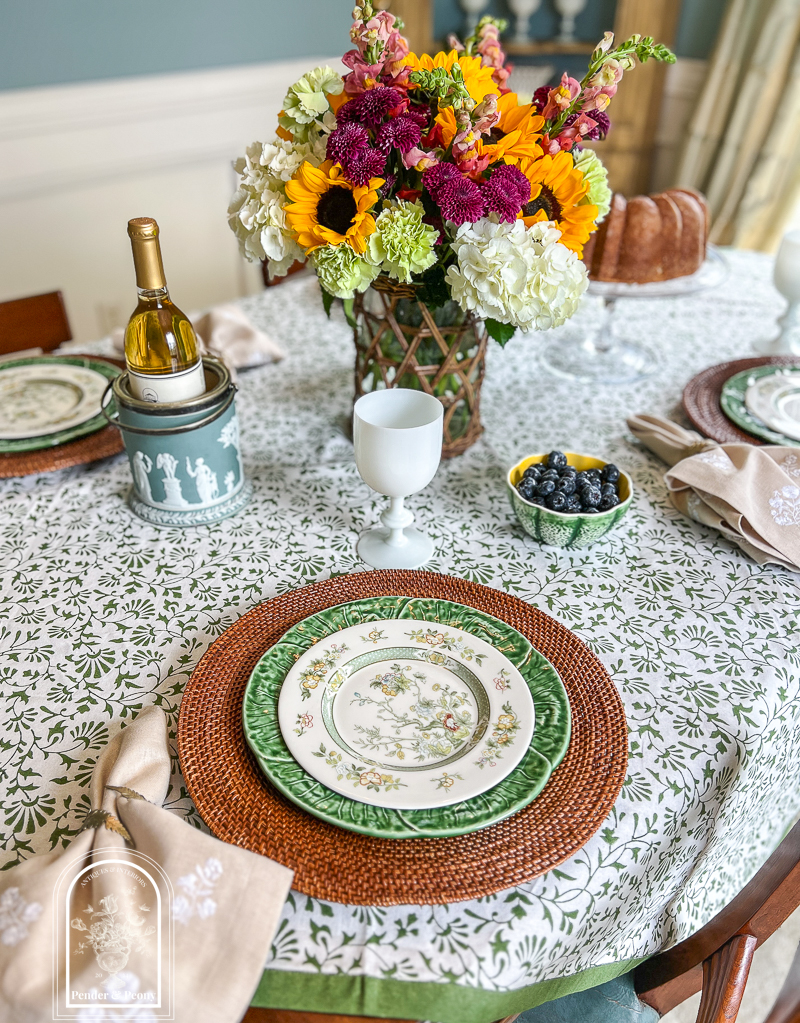 A green and white summer table with Royal Doulton china, cabbageware, linen napkins, Indian block print tablecloth, white opaline goblets, and sunflowers