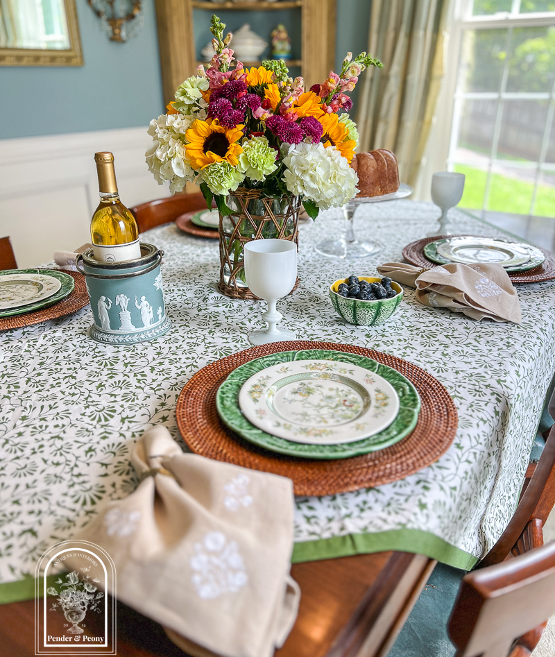 A green and white summer table with Royal Doulton china, cabbageware, linen napkins, Indian block print tablecloth, white Portieux Vallerysthal goblets, and sunflowers