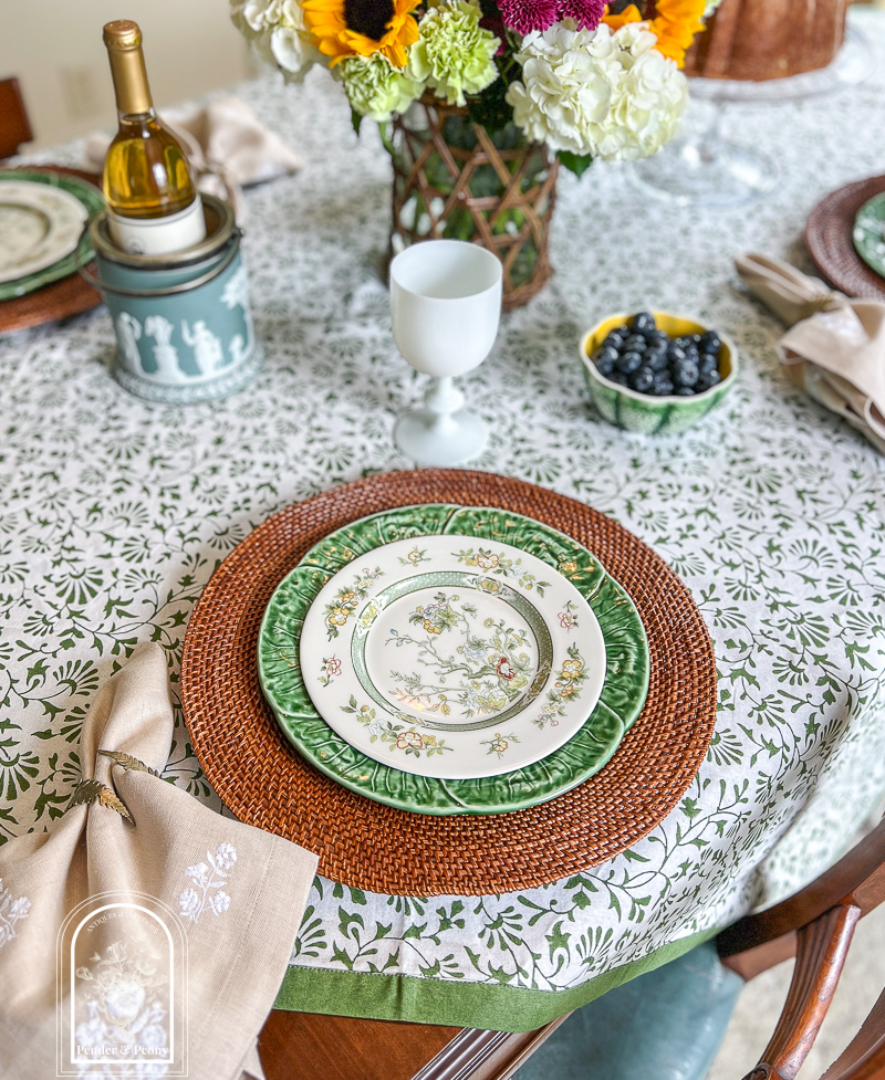 A green and white summer table with Royal Doulton china, cabbageware, linen napkins, Indian block print tablecloth, white opaline goblets, and sunflowers
