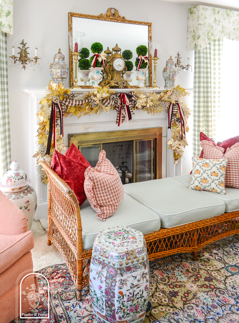 An elegant fall mantel with gold maple leaf garland, brown gingham, and burgundy velvet bows