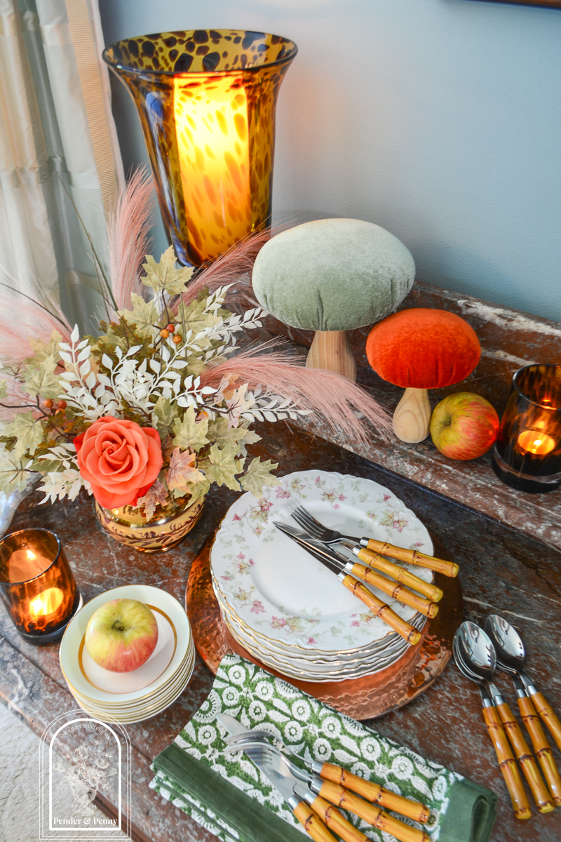 Autumn tablescape idea with maple leaf china, tortoiseshell glass, mushrooms, apples, and bamboo flatware