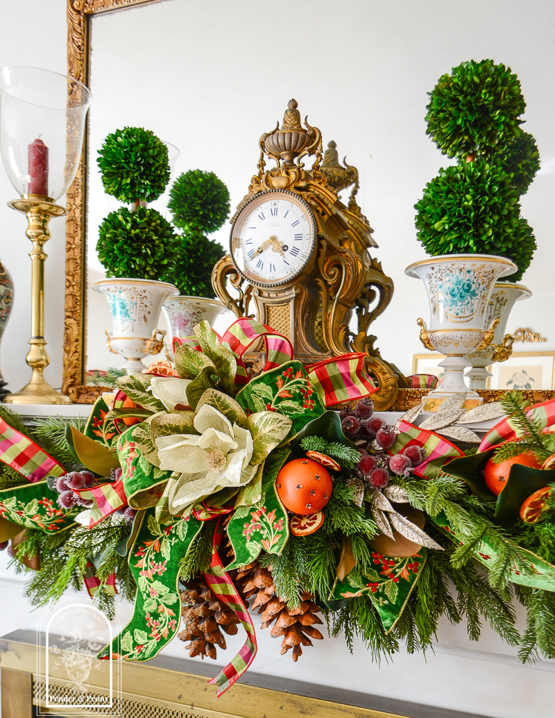 Christmas garland idea for 2026 - Old World Christmas style with Colonial Williamsburg vibes and a traditional festive feel, mixing draping cedar, magnolia, orange pomanders, gingham and velvet ribbons, and red berries.