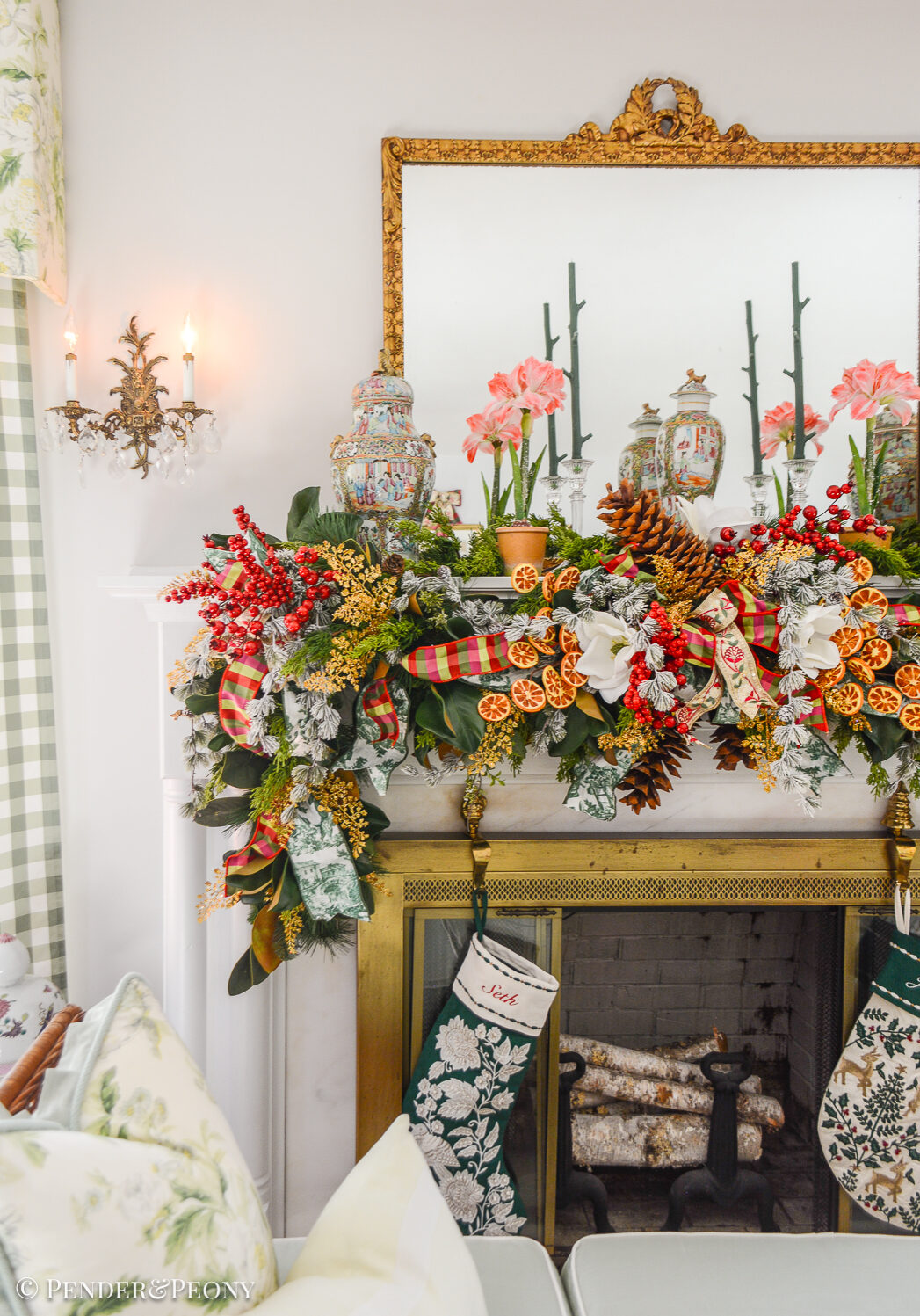 A Grand Botanical Christmas mantel decoration with DIY garland made of magnolia, pine, cedar, red berries, gold fern, orange slices, ribbon, and amaryllis.