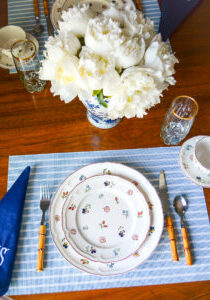 Breakfast table setting with Villeroy & Boch Petite Fleur dishes, blue and white striped placemats, navy monogrammed napkins, bamboo flatware, and white peonies in Chinese jar