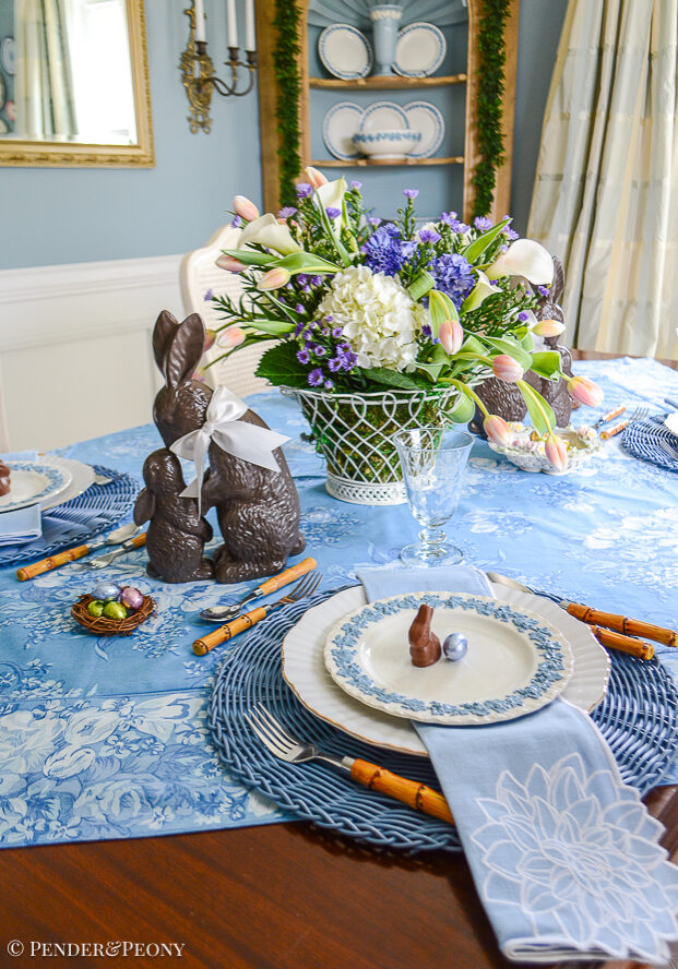 A blue and white Easter tablescape with chocolate bunnies, Wedgwood Queensware, and chintz linens