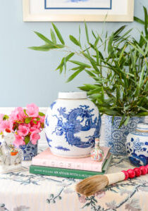 Collection of blue and white Chinese porcelains on skirted table with bamboo branches, calligraphy brush, and pink flowers - the right way to do blue and white!