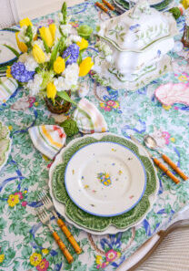An Easter table with bunnies and bows set with a vintage cloth, cabbage ware, and floral plates