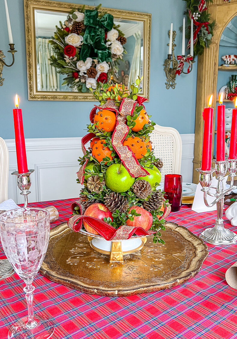 How to make a Williamsburg inspired fruit topiary with apples, mandarin oranges, pinecones, and ribbon.