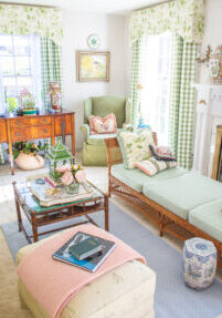 My grandmillennial living room decorated in green, white, blue, and pink with chintz and gingham window treatments, wicker furniture, and colorful accessories.