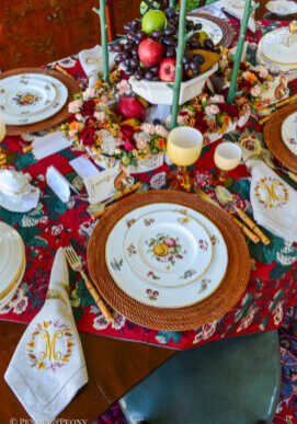 A red chintz tablecloth, hand painted fruit china, Murano goblets, Limoges porcelain, monogrammed napkins, and a surtout de table layer this elegant Thanksgiving tablescape