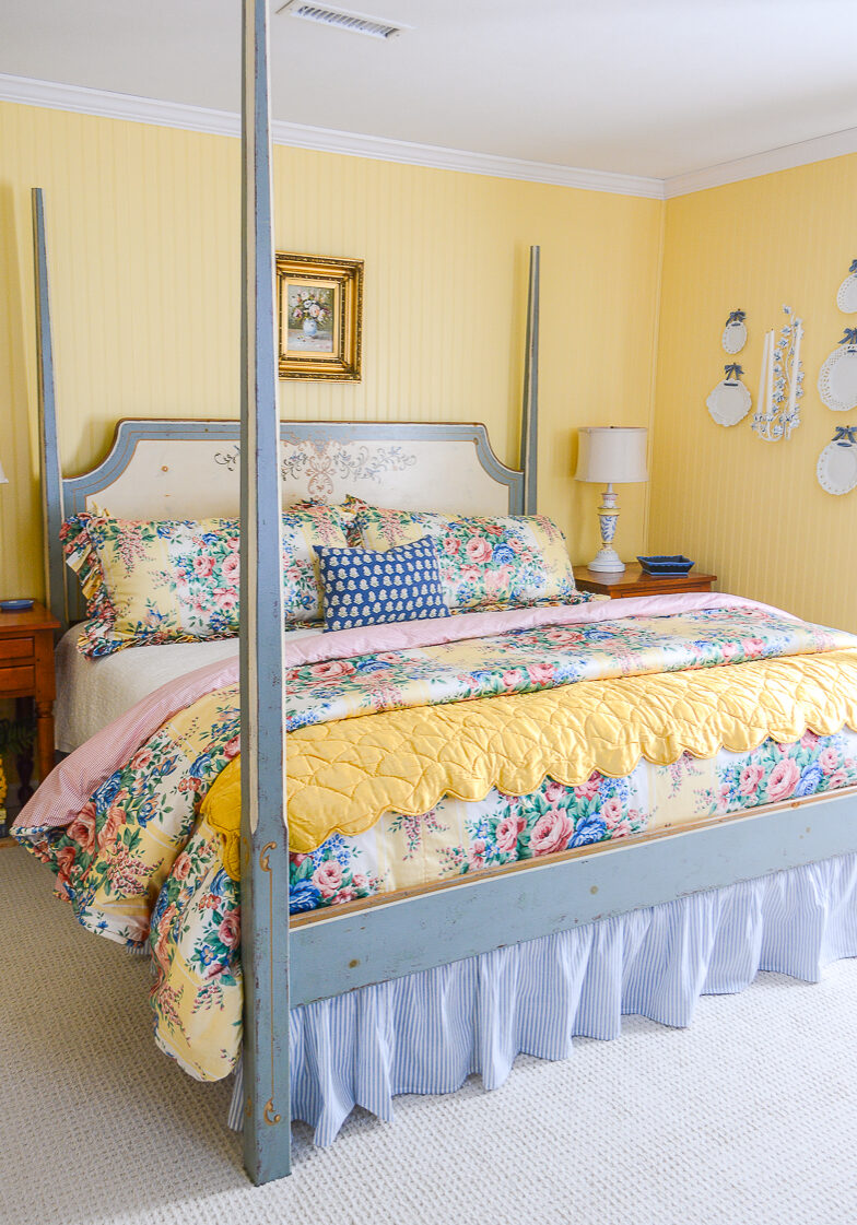 A cozy happy guest bedroom decorated in yellow and blue with floral chintz bedding, hand painted furniture, original art, and anitques!