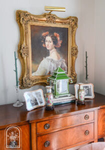 Sideboard display with portrait and lantern arranged symmetrically to combat cluttered feel