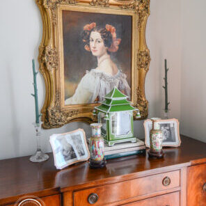 Sideboard display with portrait and lantern arranged symmetrically to combat cluttered feel