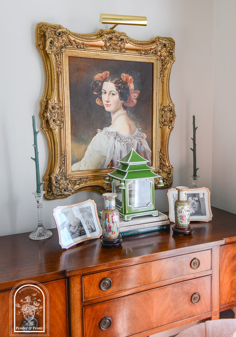 Sideboard display with portrait and lantern arranged symmetrically to combat cluttered feel