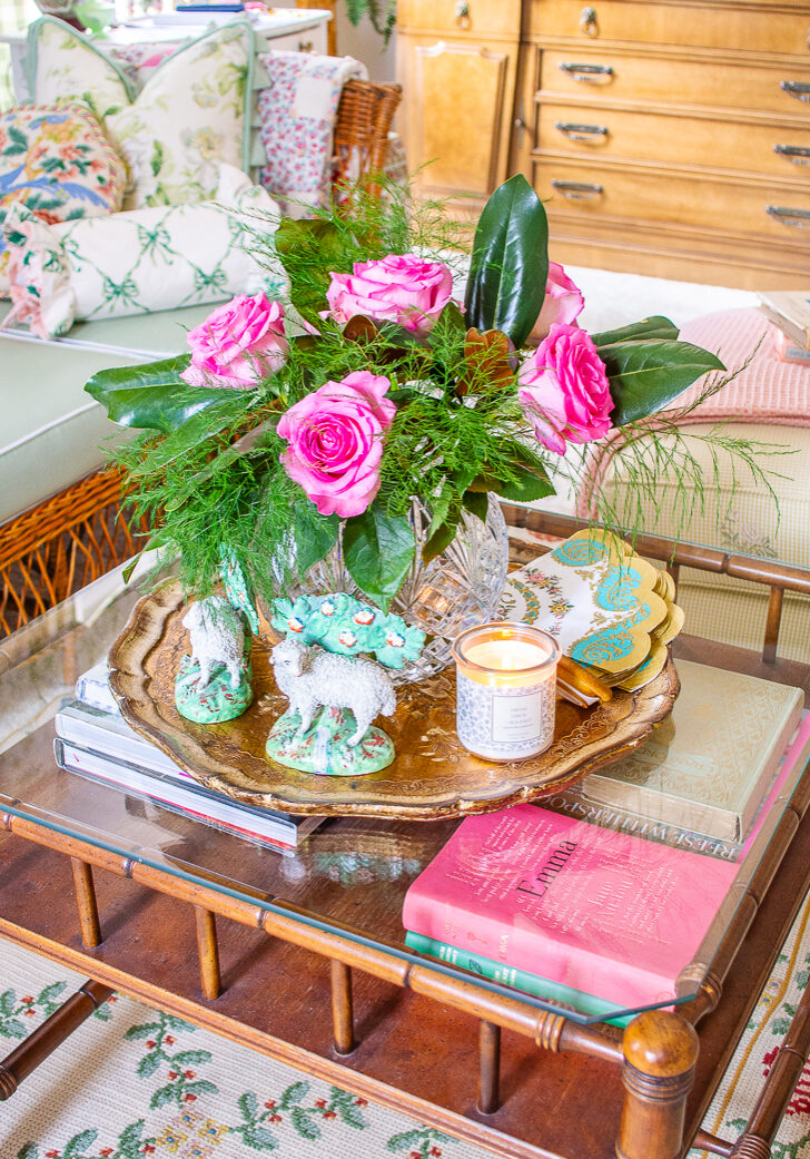 Coffee table in grandmillennial living room showing how to mix high and low end decor with inexpensive books and candles paired with a Waterford crystal vase and Staffordshire sheep