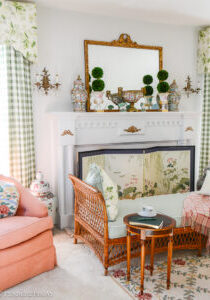 Katherine's collected living room with traditional columned mantel, French gilt mirror, Rose Medallion, and wicker daybed