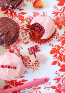 Red velvet cupcakes with strawberry cream cheese frosting on red and pink floral paper