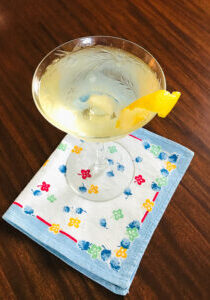 An effortless French 75 champagne cocktail in coupe with floral linen napkin